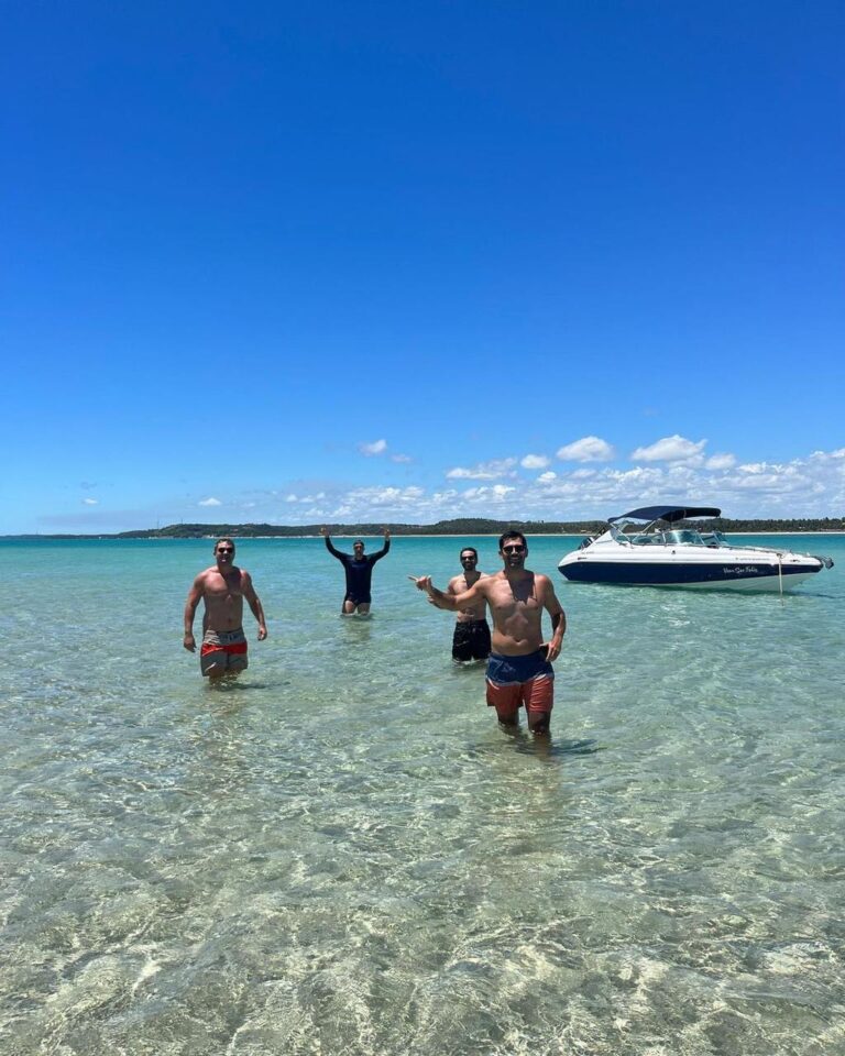 Quatro amigos na piscina natural de Japaratinga de fundo a imagem da lancha