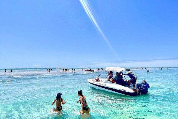 Amigas ao lado da lancha na Piscina Natural de Japaratinga