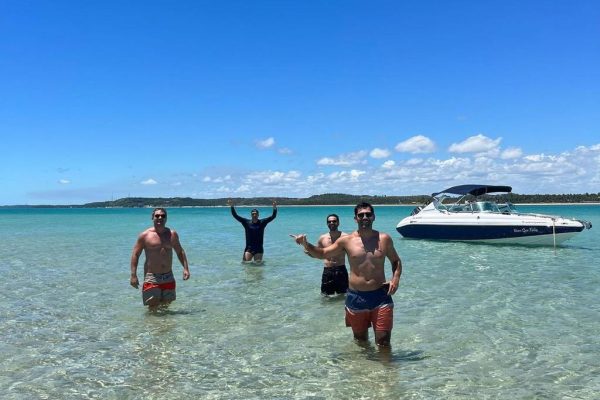 Quatro amigos na piscina natural de Japaratinga de fundo a imagem da lancha